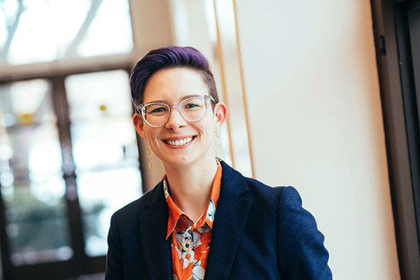 White female faculty member with glasses smiling at the camera